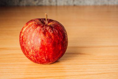Kırmızı elma dramatik aydınlatma, ahşap bir masa üzerinde seçici odak.