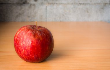 Kırmızı elma dramatik aydınlatma, ahşap bir masa üzerinde seçici odak.