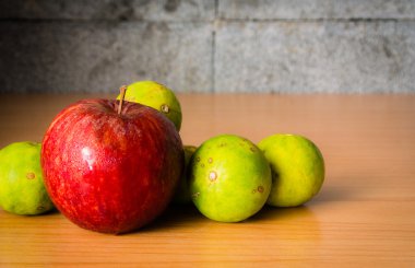 Kırmızı elma ve limon dramatik aydınlatma, ahşap bir masa üzerinde seçici odak.