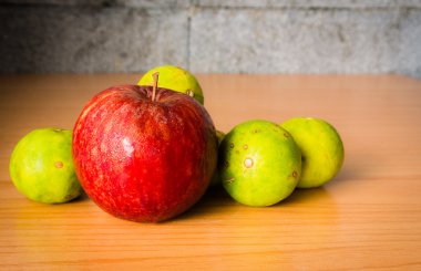 Kırmızı elma ve limon dramatik aydınlatma, ahşap bir masa üzerinde seçici odak.
