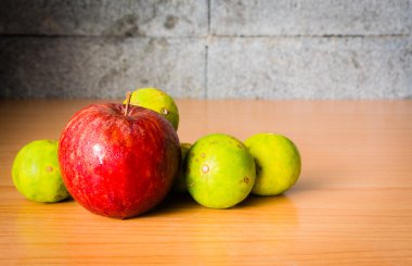 Kırmızı elma ve limon dramatik aydınlatma, ahşap bir masa üzerinde seçici odak.