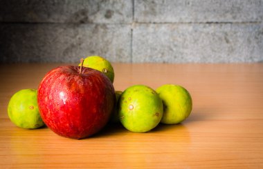 Kırmızı elma ve limon dramatik aydınlatma, ahşap bir masa üzerinde seçici odak.