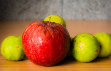 Kırmızı elma ve limon dramatik aydınlatma, ahşap bir masa üzerinde seçici odak.