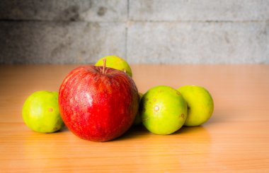 Kırmızı elma ve limon dramatik aydınlatma, ahşap bir masa üzerinde seçici odak.