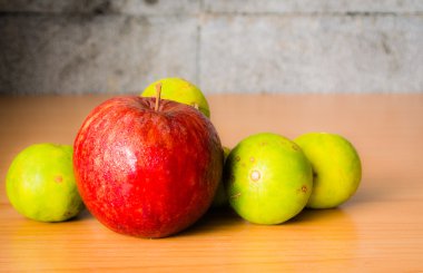 Kırmızı elma ve limon dramatik aydınlatma, ahşap bir masa üzerinde seçici odak.