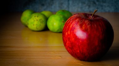 Kırmızı elma ve limon dramatik aydınlatma, ahşap bir masa üzerinde seçici odak.