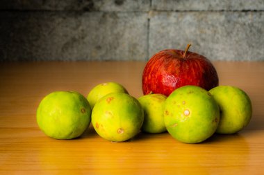 Kırmızı elma ve limon dramatik aydınlatma, ahşap bir masa üzerinde seçici odak.