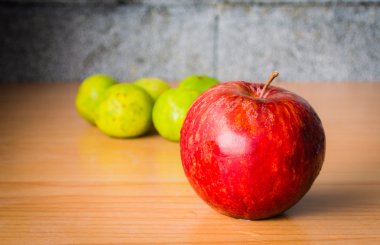 Kırmızı elma ve limon dramatik aydınlatma, ahşap bir masa üzerinde seçici odak.