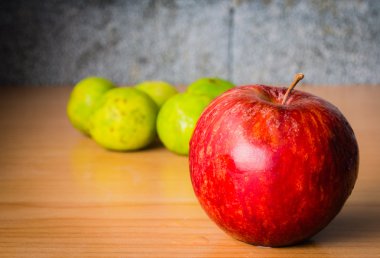 Kırmızı elma ve limon dramatik aydınlatma, ahşap bir masa üzerinde seçici odak.
