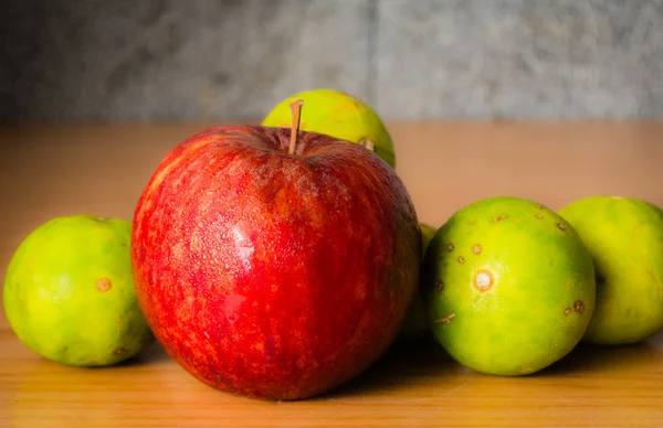 Kırmızı elma ve limon dramatik aydınlatma, ahşap bir masa üzerinde seçici odak.