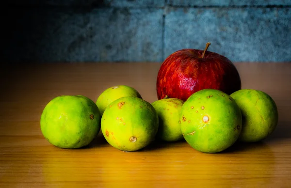 Kırmızı elma ve limon dramatik aydınlatma, ahşap bir masa üzerinde seçici odak.
