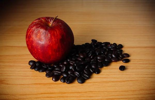 Kırmızı elma ve dramatik aydınlatma, seçici odak, Vintage sesi ile ahşap bir masa üzerinde kahve çekirdeği