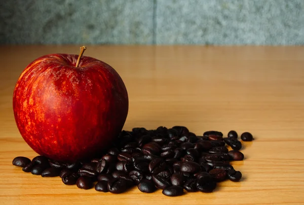 Kırmızı elma ve dramatik aydınlatma, seçici odak, Vintage sesi ile ahşap bir masa üzerinde kahve çekirdeği