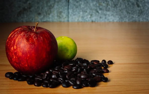 Manzana roja, lima y grano de café en una madera con iluminación dramática, enfoque selectivo, tono vintage . Imagen de archivo