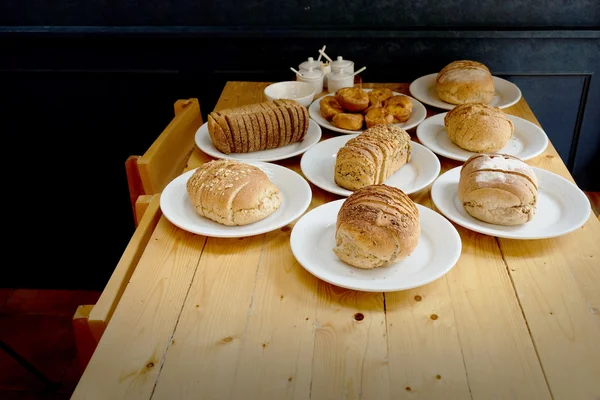 Pane al forno su piatto bianco e tavolo in legno — Foto Stock