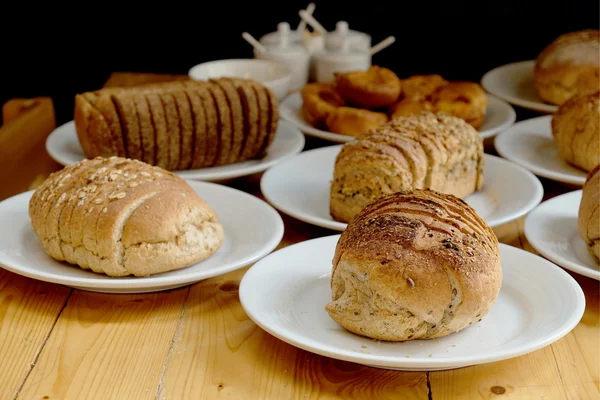 Gebackenes Brot auf weißem Teller und Holztisch — Stockfoto