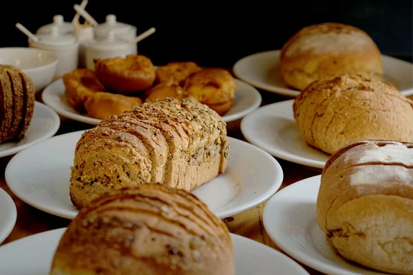 Pão assado em prato branco e mesa de madeira — Fotografia de Stock