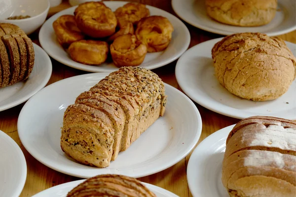 Pane al forno su piatto bianco e tavolo in legno — Foto Stock