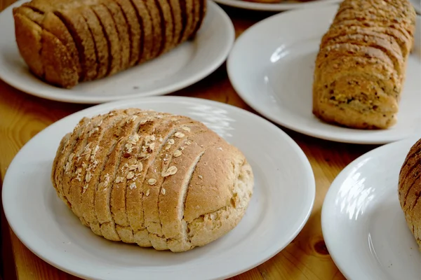 Pane al forno su piatto bianco e tavolo in legno — Foto Stock