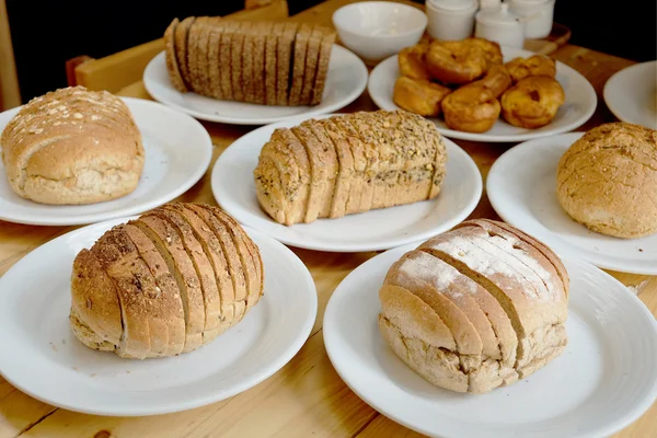 Запечений хліб на білій тарілці та дерев'яний стіл — стокове фото
