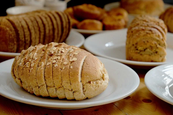 Gebackenes Brot auf weißem Teller und Holztisch — Stockfoto