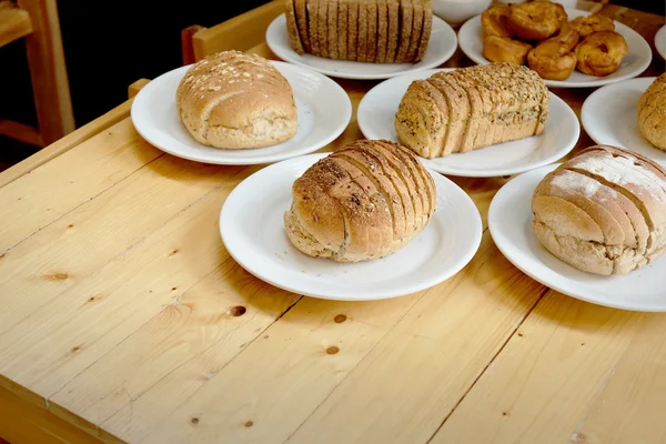 Pane al forno su piatto bianco e tavolo in legno — Foto Stock