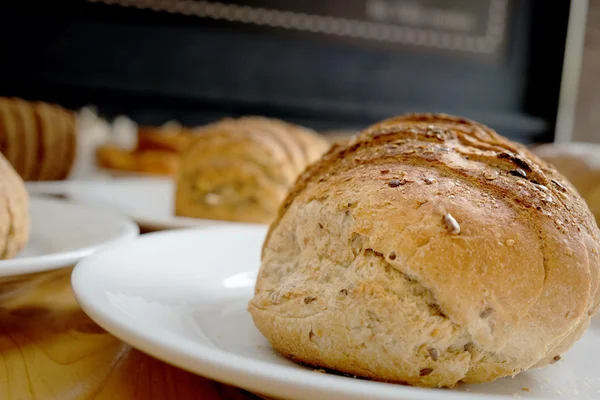 Pane al forno su piatto bianco e tavolo in legno — Foto Stock