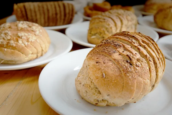 Gebackenes Brot auf weißem Teller und Holztisch — Stockfoto