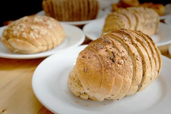 Pan al horno en plato blanco y mesa de madera —  Fotos de Stock
