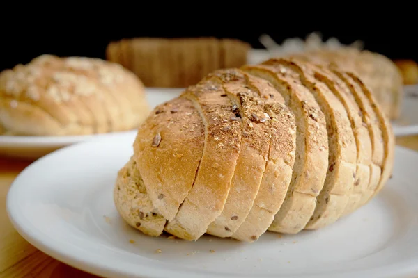 Gebackenes Brot auf weißem Teller und Holztisch — Stockfoto