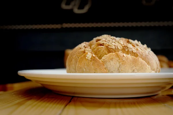 Pane al forno su piatto bianco e tavolo in legno — Foto Stock