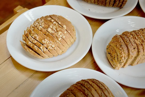 Gebackenes Brot auf weißem Teller und Holztisch — Stockfoto