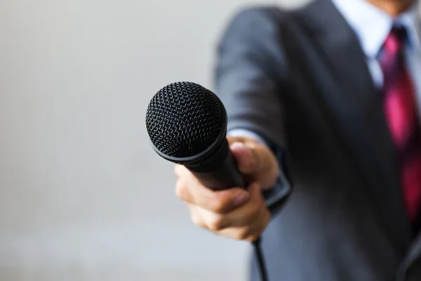 Человек в деловом костюме держит микрофон ведения бизнеса — стоковое фото