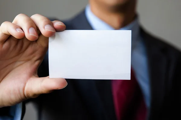 Beyaz boş kartvizit holding iş elbiseli genç adam. 