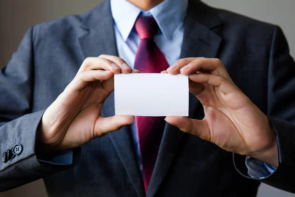 Junger Mann im Business-Anzug mit weißer Visitenkarte. — Stockfoto