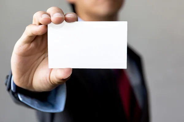 Jovem em terno de negócios segurando cartão de visita em branco . — Fotografia de Stock