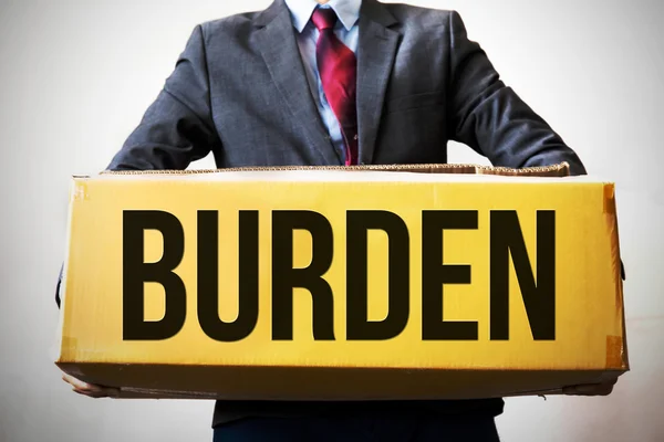 Business man carrying an old box saying "BURDEN" - indicates debt and business burden — Stock Photo, Image