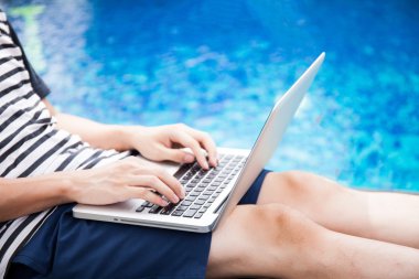 Bir dizüstü bilgisayar havuzda tatile - herhangi bir yerde iş ve internet iş kavramı kullanan adam