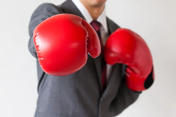 Empresario en guantes de boxeo lanzando un puñetazo aislado sobre fondo blanco — Foto de Stock