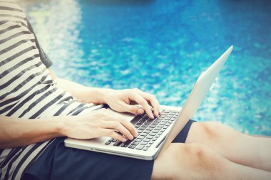 Bir dizüstü bilgisayar havuzda tatile - herhangi bir yerde iş ve internet iş kavramı kullanan adam