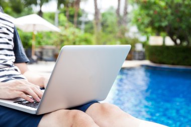 Bir dizüstü bilgisayar havuzda tatile - herhangi bir yerde iş ve internet iş kavramı kullanan adam