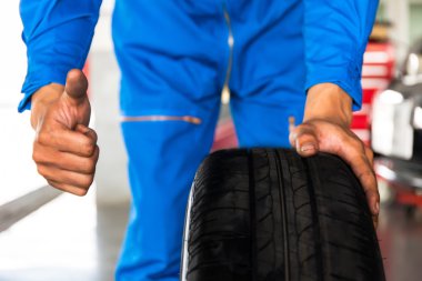 Araba garajda araba tekerleği yukarı işareti ile tutarak makinist