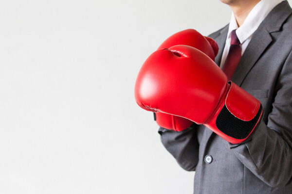 Бизнесмен в боксёрских перчатках охраняется на белом фоне
