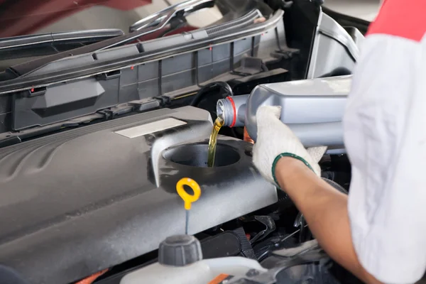 Mecánico de mantenimiento vertiendo nuevo lubricante de aceite en el motor del coche —  Fotos de Stock