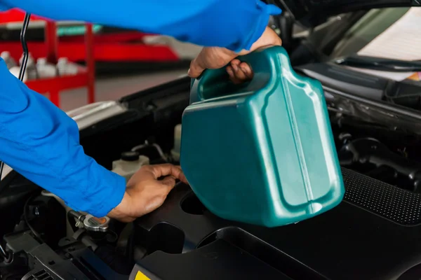 Serwisowanie mechanik wlewając nowy smar olej do silnika samochodu — Zdjęcie stockowe