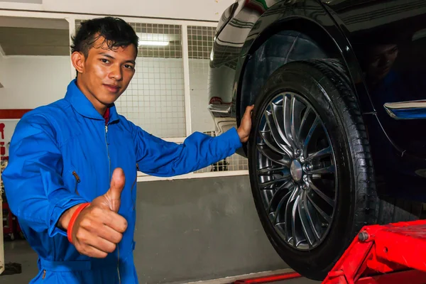 Joyeux jeune technicien abandonnant les pouces tout en remplaçant les pneus — Photo