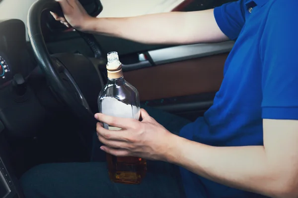 Mężczyzna trzyma butelkę alkoholu podczas jazdy w tonie vintage — Zdjęcie stockowe