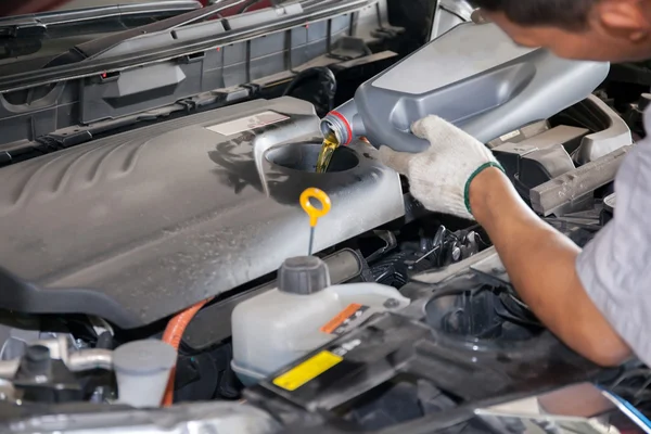 Mecánico de mantenimiento vertiendo nuevo lubricante de aceite en el motor del coche —  Fotos de Stock