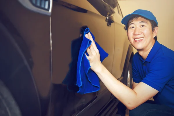 Nettoyant voiture asiatique en uniforme bleu, laver une voiture avec le sourire (ton vintage ) — Photo