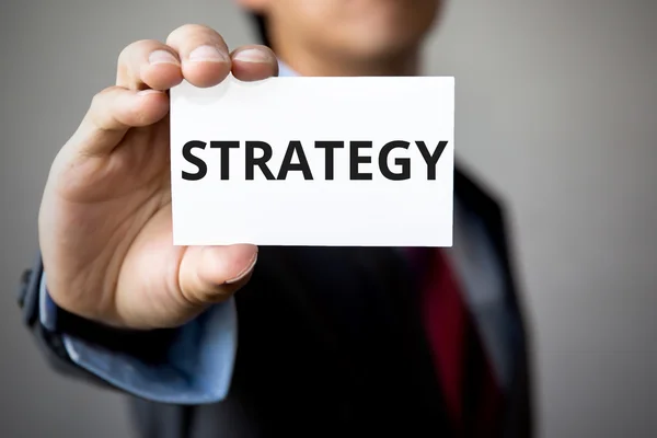 Üzletember "Stratégia" szó a fehér kártya bemutatása — Stock Fotó